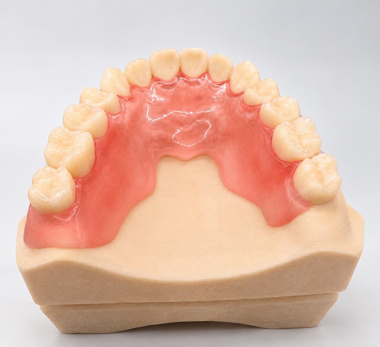 Upper partial denture with a pink base and replacement teeth, viewed from above