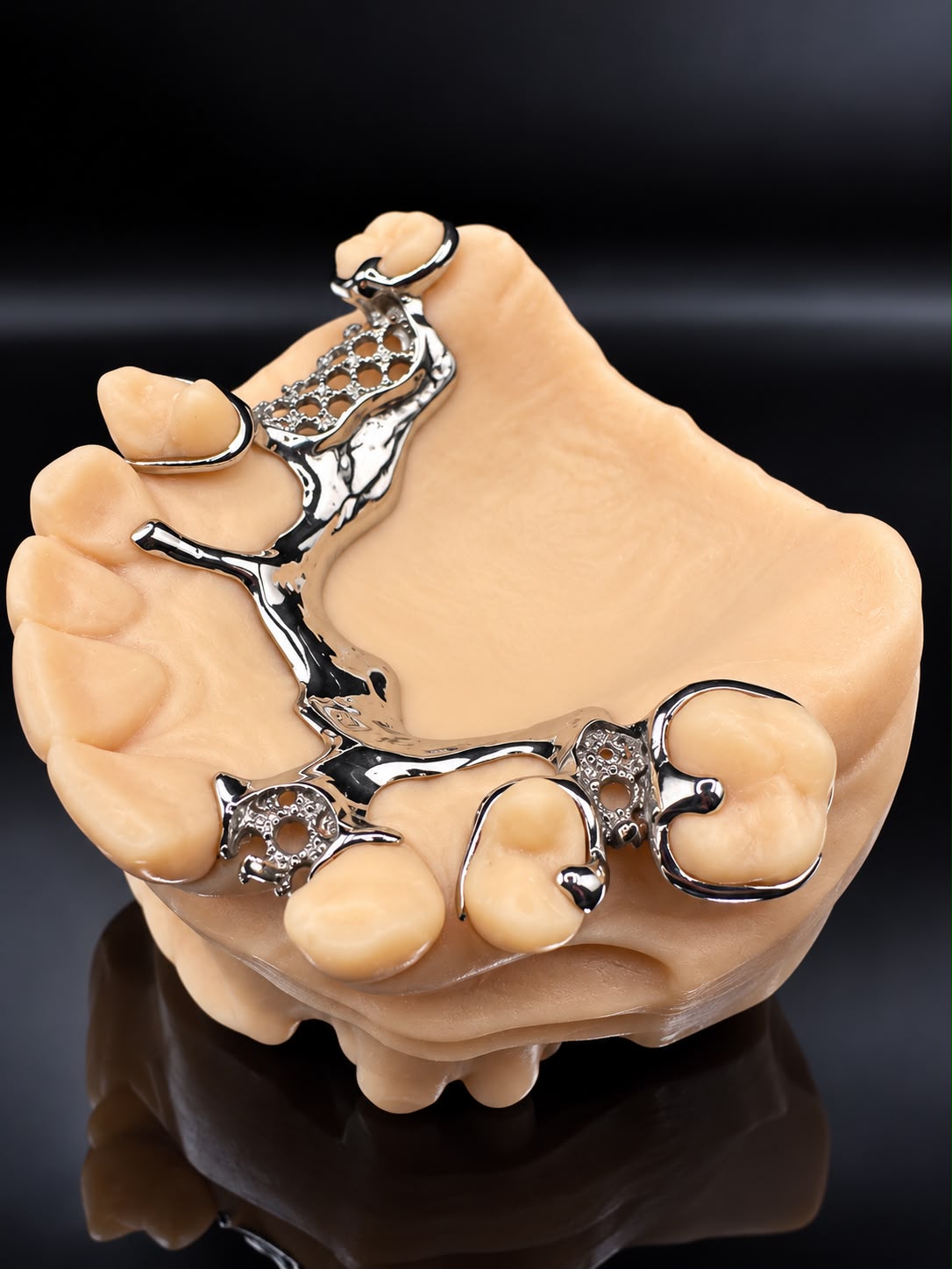 Polished metal partial denture framework showing its connector, clasps and mesh sections on a dental model